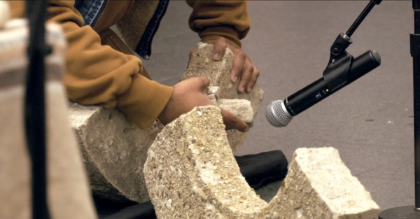 A close up of a person holding broken pieces of concrete up to a microphone