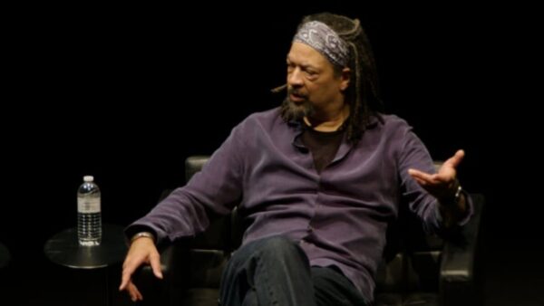 A man sits in a chair on a black stage