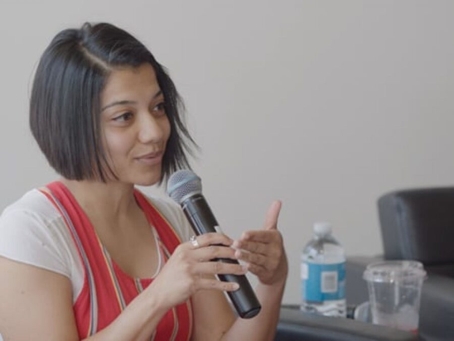 A female presenting person holds a microphone