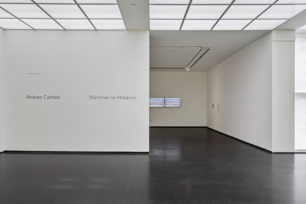 Entrance to a gallery space with the exhibition name on the left side of the entrance reading Andrea Carlson Shimmer on Horizons