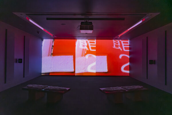 A double image of a red sign with characters on it is projected onto a screen in a dark room