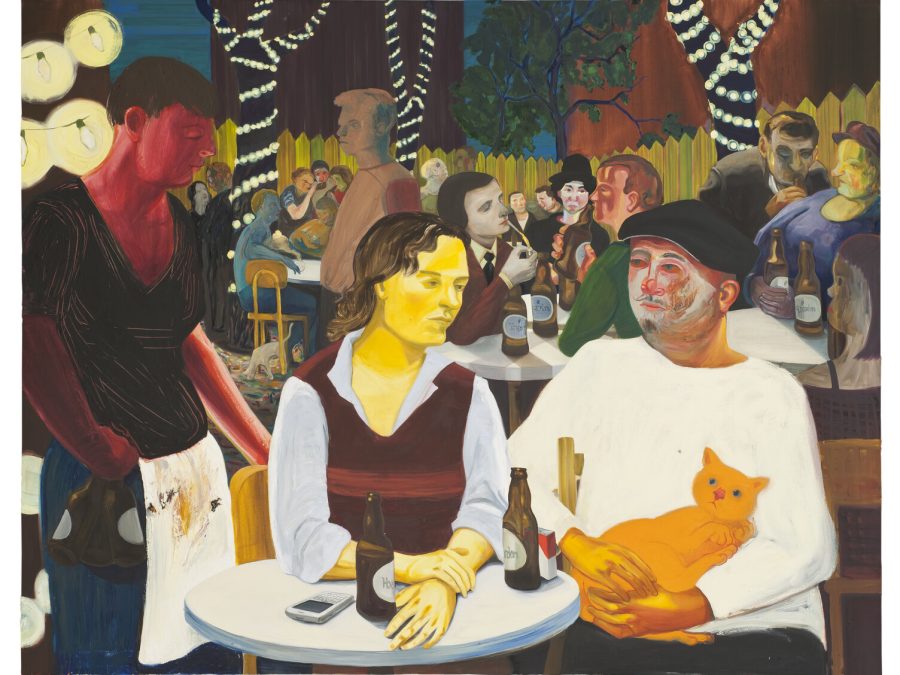 Two people sit at a cafe table in a lively, fenced-in garden with bottles in front of them as a server stands nearby. The person on the right has faint mime makeup on and holds a cat.