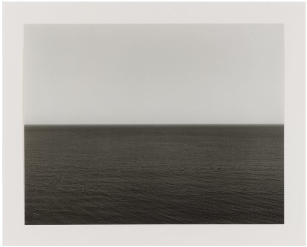 Black-and-white image of a body of water and the sky; the horizon line is aligned with the middle of the image.