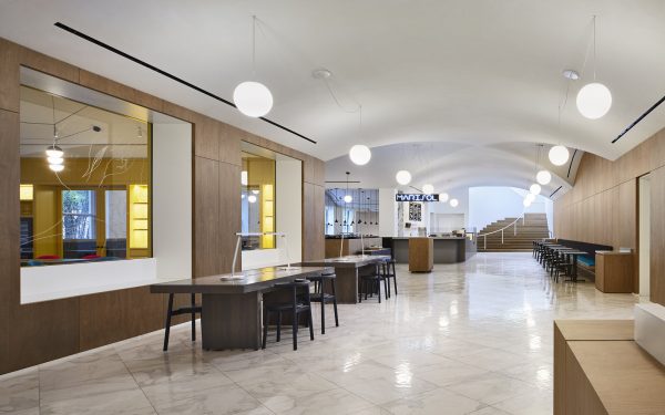 A bright cavernous space with a white marble floor and various seating areas leads to a counter with a sign overhead reading Marisol