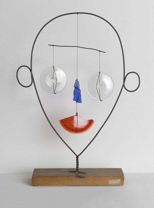 wire form of a face with clear eyes, a blue nose, and a red mouth hanging from a balanced mobile