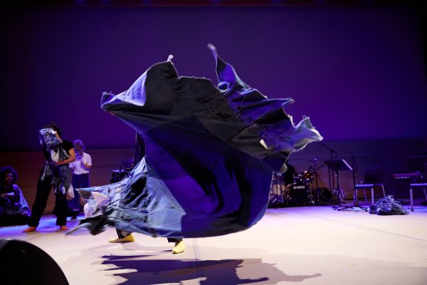 A whirl of purple fabric takes center stage against a purple-lit background.