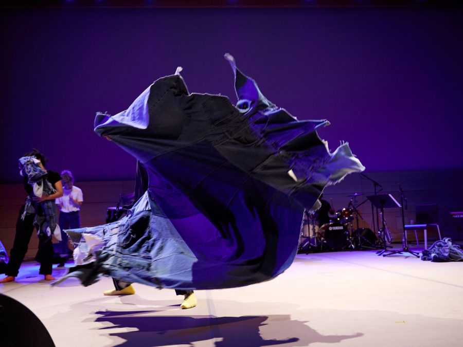 A whirl of purple fabric takes center stage against a purple-lit background.