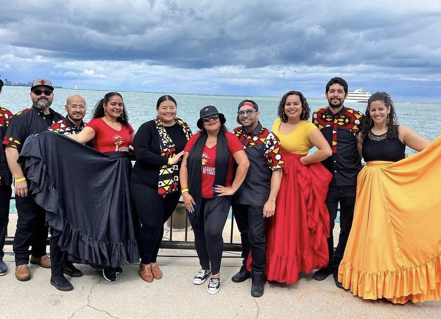 Photo of a group of bomba dancers posed in front of a large body of water.