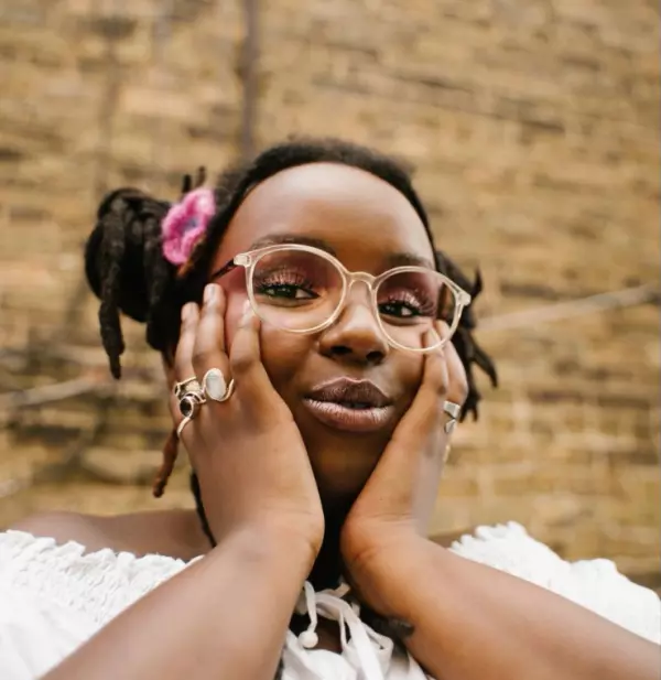 portrait of Bonita Appleblunt, smiling, hands cupping face