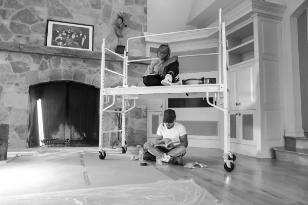 Portrait of Naïla Opiangah seated on scaffolding, Chance the Rapper sits underneath cross-legged