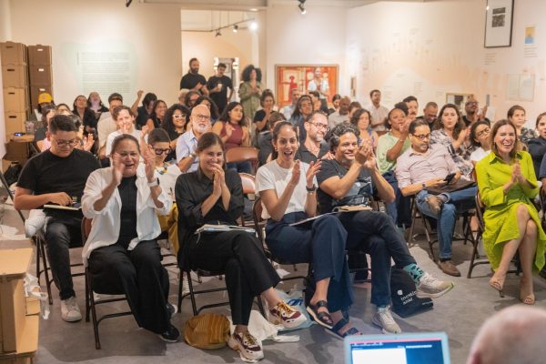 A group of young people clapping and smiling while sitting in chairs.