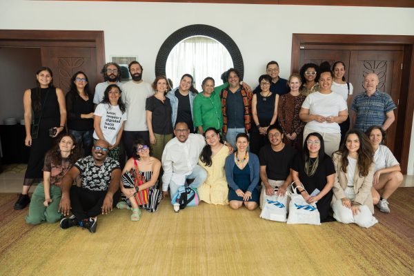 A group of people kneeling on the floor and standing smile for a photo.