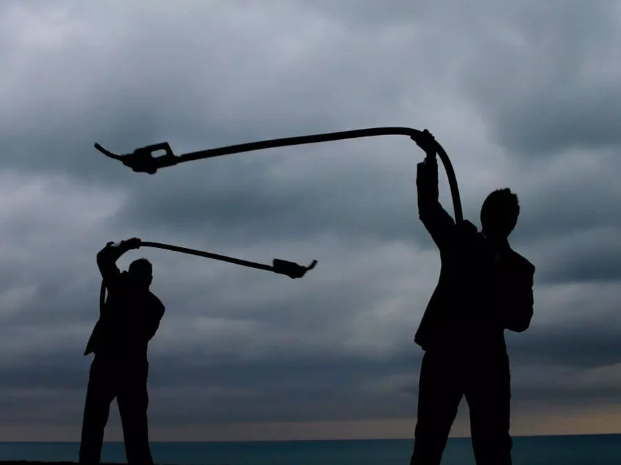 Two silhouetted figures twirl fuel hoses like lassos