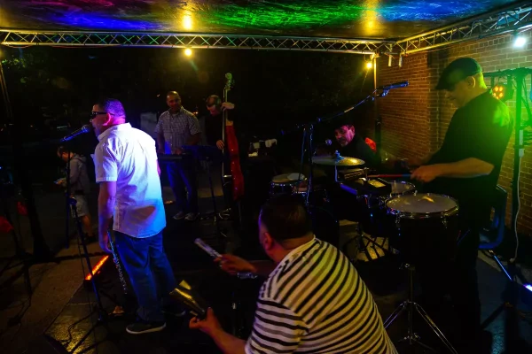 musicians play a live set in a dark room with blue, yellow, and green lighting