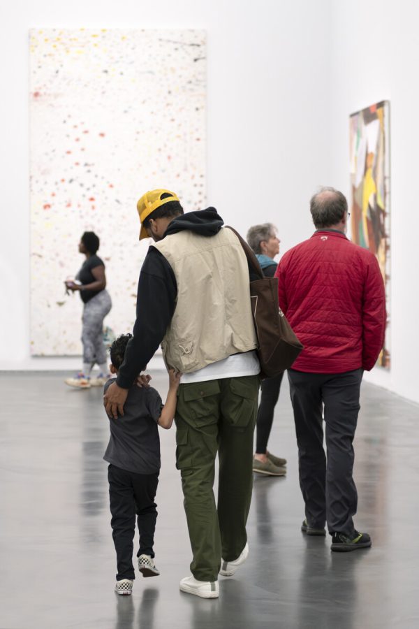 An adult guides a small child through a busy gallery space.