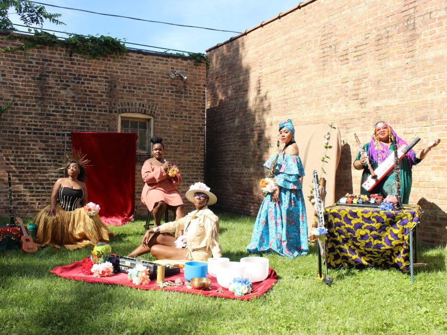 Five woman post in a yard surrounded by brick walls.