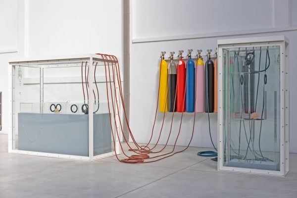 Tanks filled with a liquid are connected by wires and multicolored gas tanks.