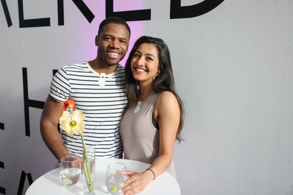 Two people pose for the camera while standing at a cocktail table.