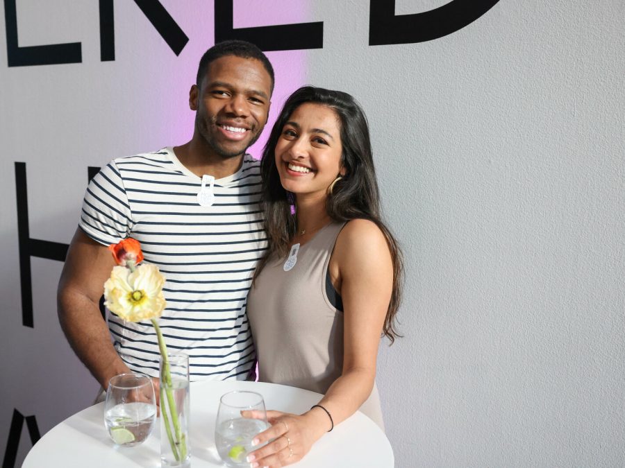 Two people pose for the camera while standing at a cocktail table.