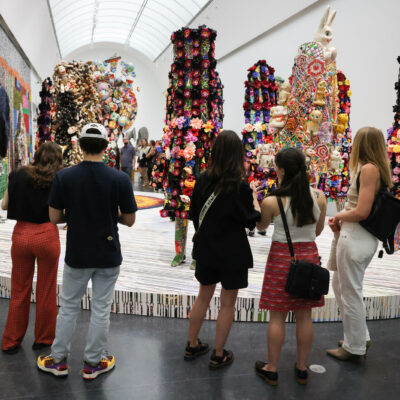 A group of people stand in front of a platform of colorful costumed mannequins