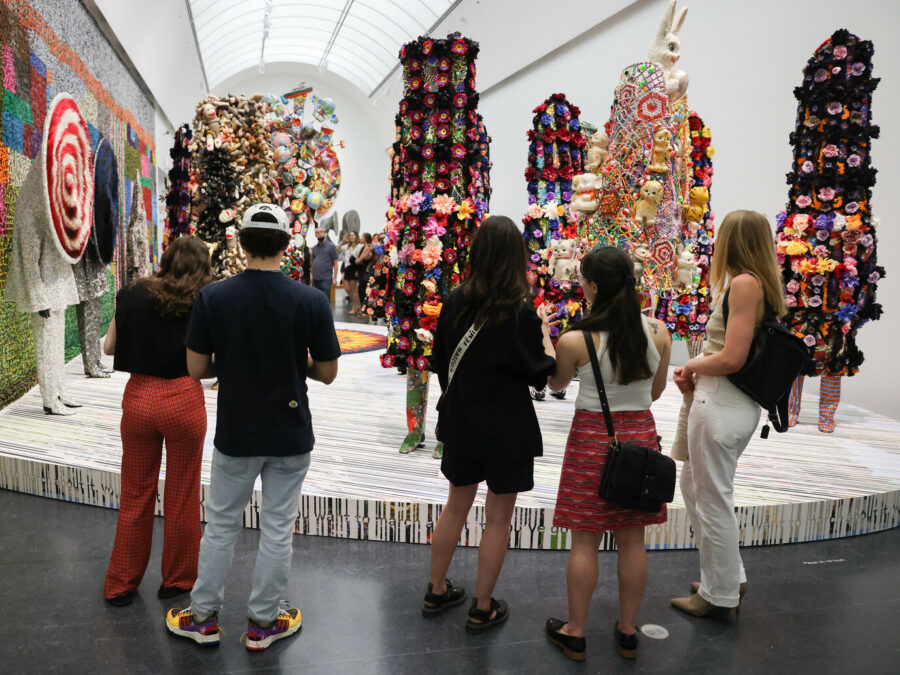 A group of people stand in front of a platform of colorful costumed mannequins