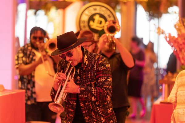A brass band plans in the middle of an orange-lit room