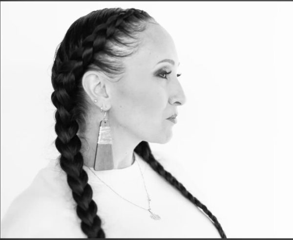 Black and white profile portrait of a female-presenting person with long dark hair braided into two french braids that come down each side, extending past the photo frame