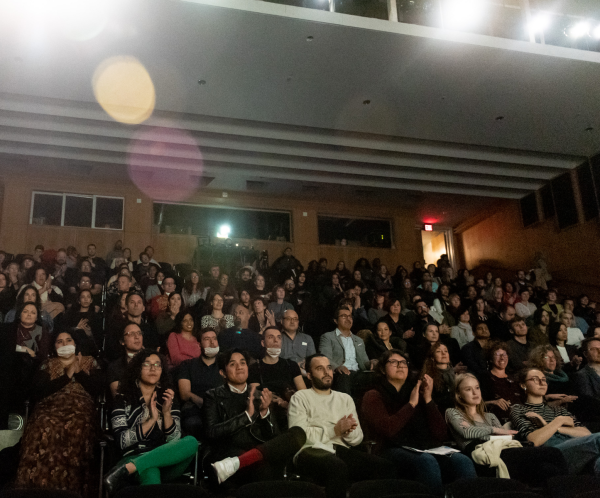 A group of people sitting in a tiered row theater