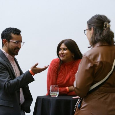 Three people gather around a cocktail table.