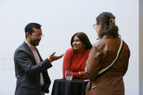 Three people gather around a cocktail table.