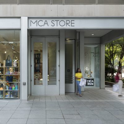 The exterior of the MCA Store with two shoppers exiting with bags