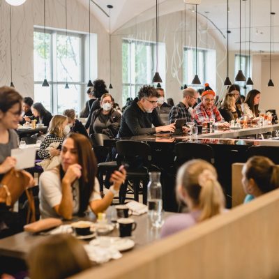 Diners seated at tables and a bar in a bustling, bright restaurant