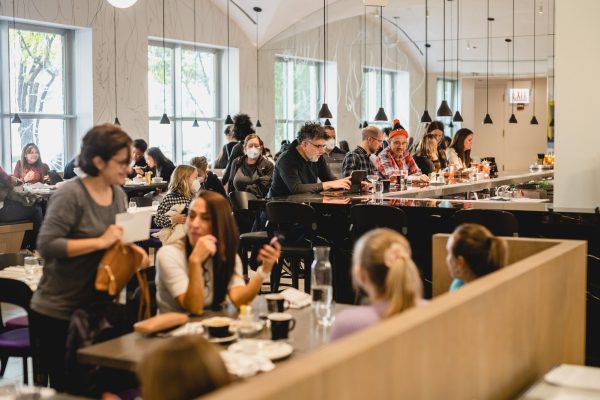 Diners seated at tables and a bar in a bustling, bright restaurant