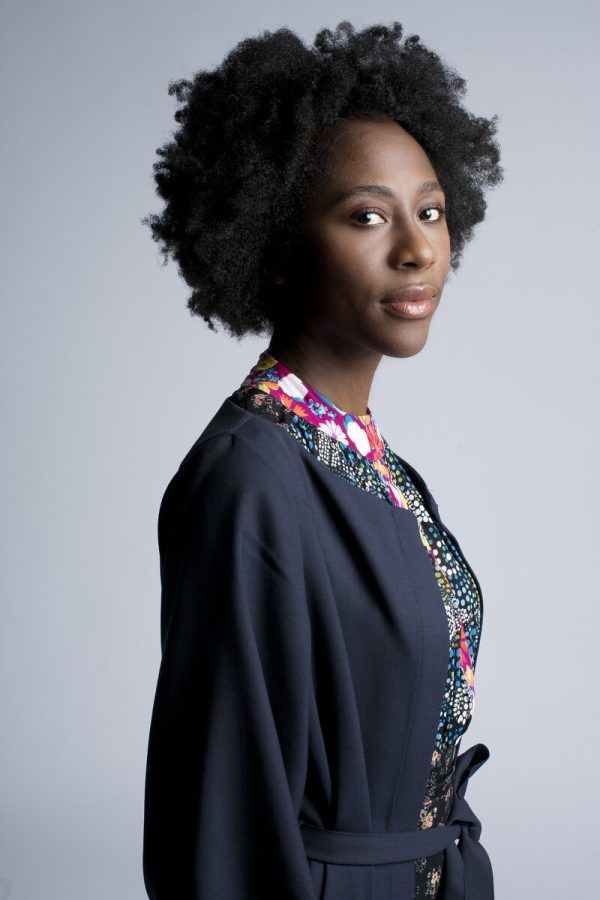 Curator Naomi Beckwith, a Black woman with natural style hair, turns to look at the camera in a portrait.