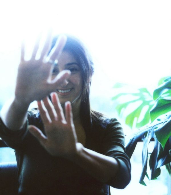 A slightly overexposed photo of a person blocking part of their faces with both hands.