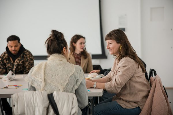 Image of four individuals sitting at tables in conversation.