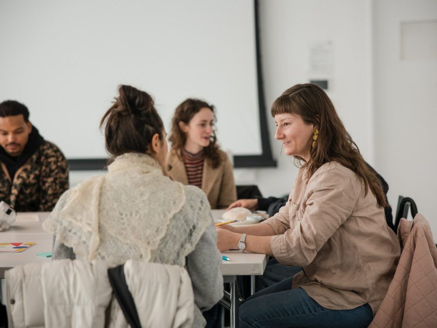 Image of four individuals sitting at tables in conversation.