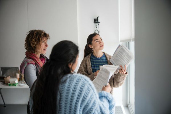 Photo of three people with papers in their hands conversing.