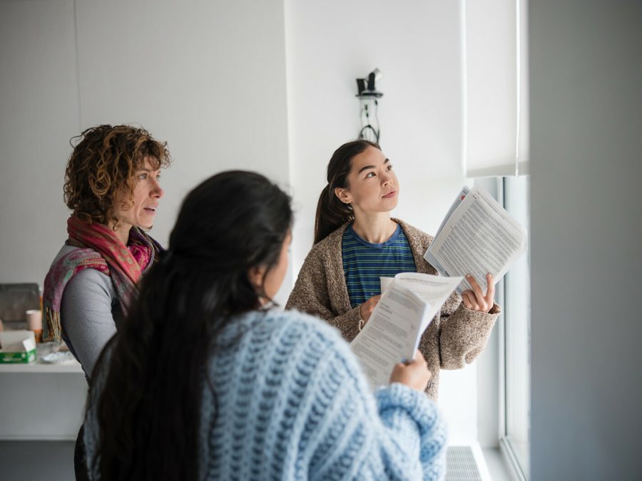 Photo of three people with papers in their hands conversing.