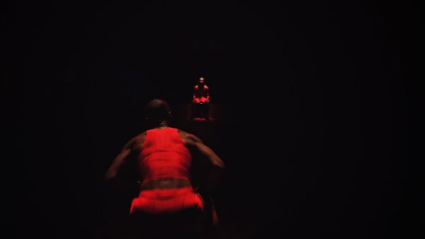 Photo of two performers dressed in red in dark room.