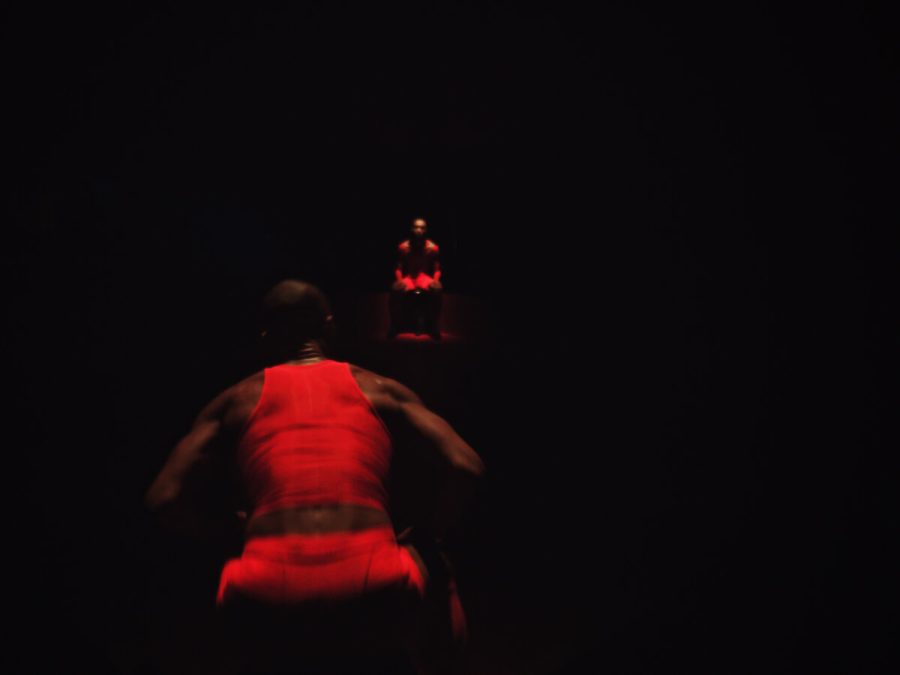 Photo of two performers dressed in red in dark room.