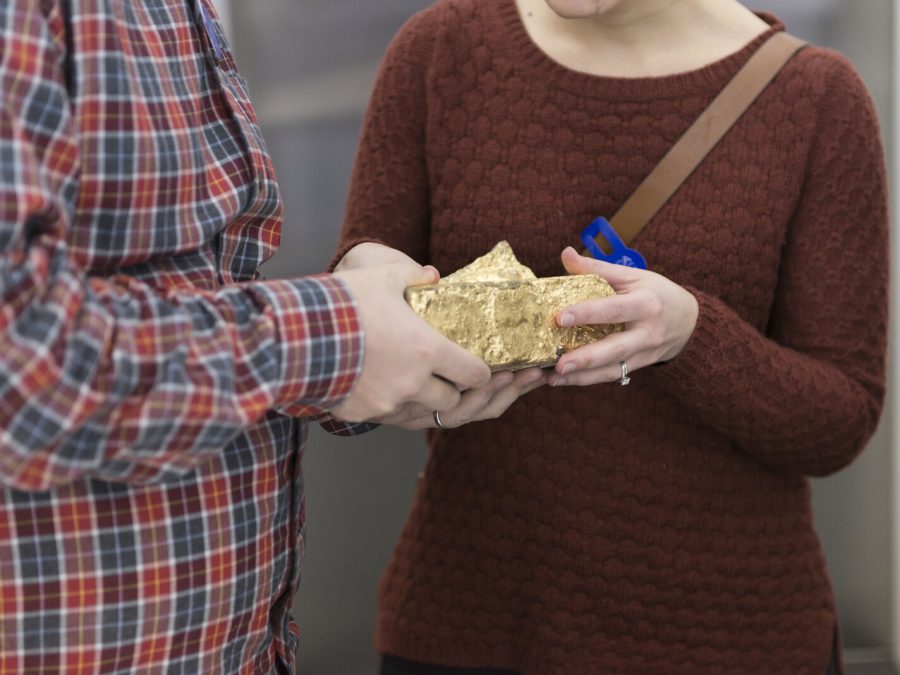 Close up of two people's torsos as they hold a rock together