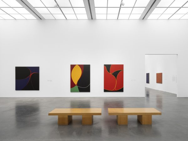 Gallery with three large paintings hung on the walls. A view into another room through a large doorway reveals two more paintings.