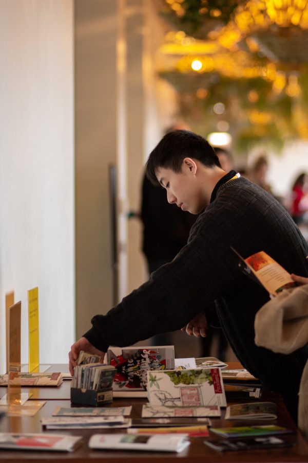 A teen explores tables filled with zines.