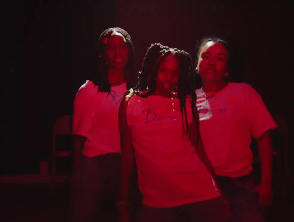 Three girls lit with a red, filtered light.