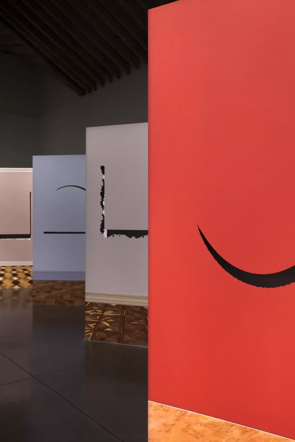 Close up detail of artwork that appears as sections of different colored walls with baseboard and flooring