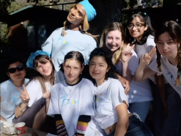 8 women in matching t-shirts pose varied expressions and gestures
