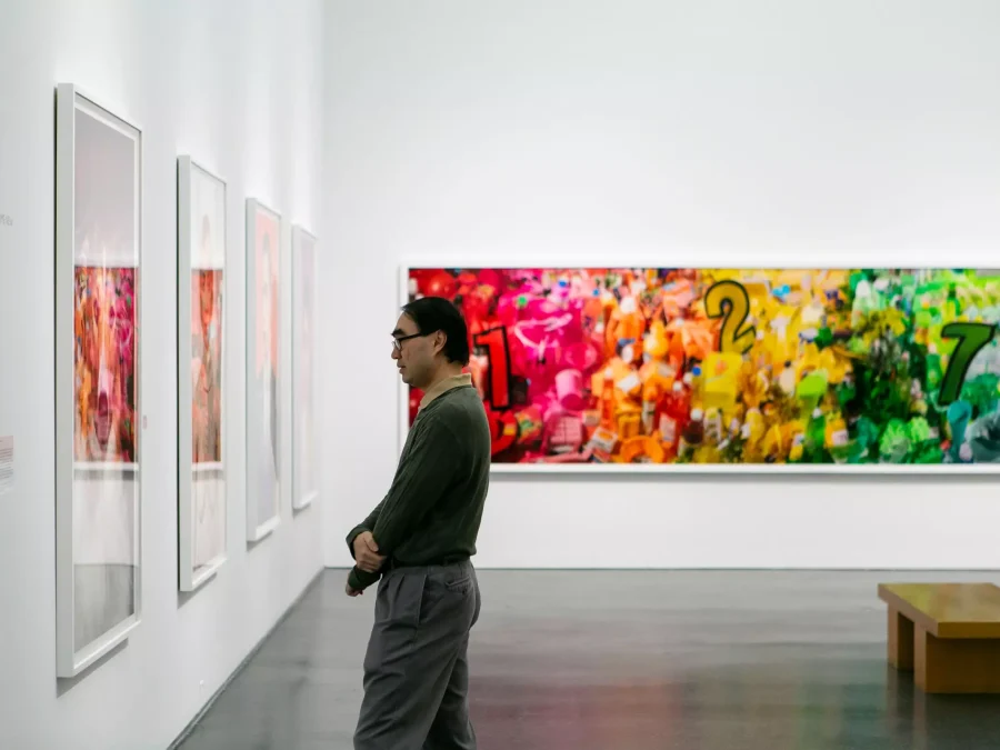 A man stands in profile intently browsing art in gallery