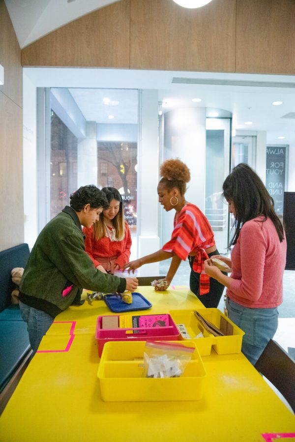 four teens work on a project gathered around a table