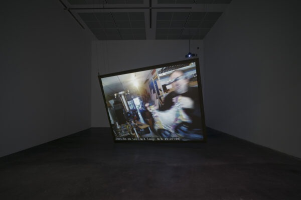 Blurry video displays on a large cock-eyed video screen in a dark room
